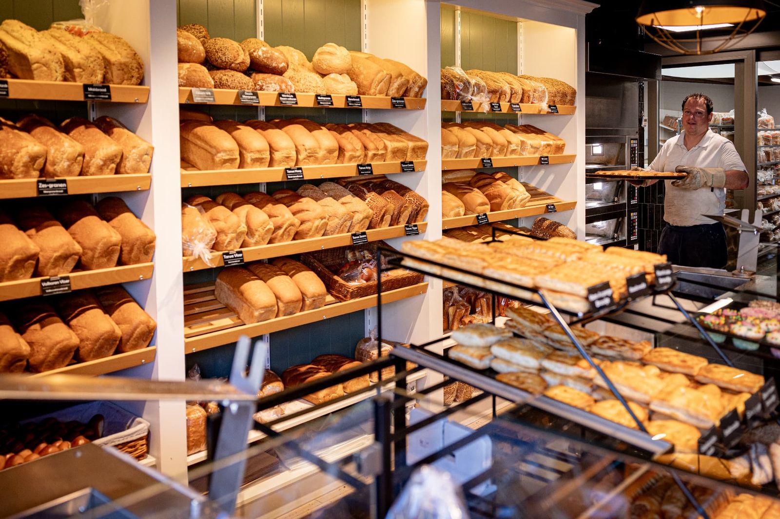 Bakker van Bakkerij van Hassel loopt met een vers gebakken plaat door de winkel in Wernhout